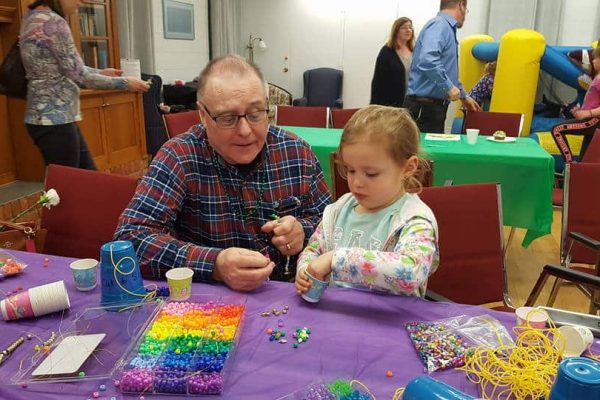 senior helps child with craft project